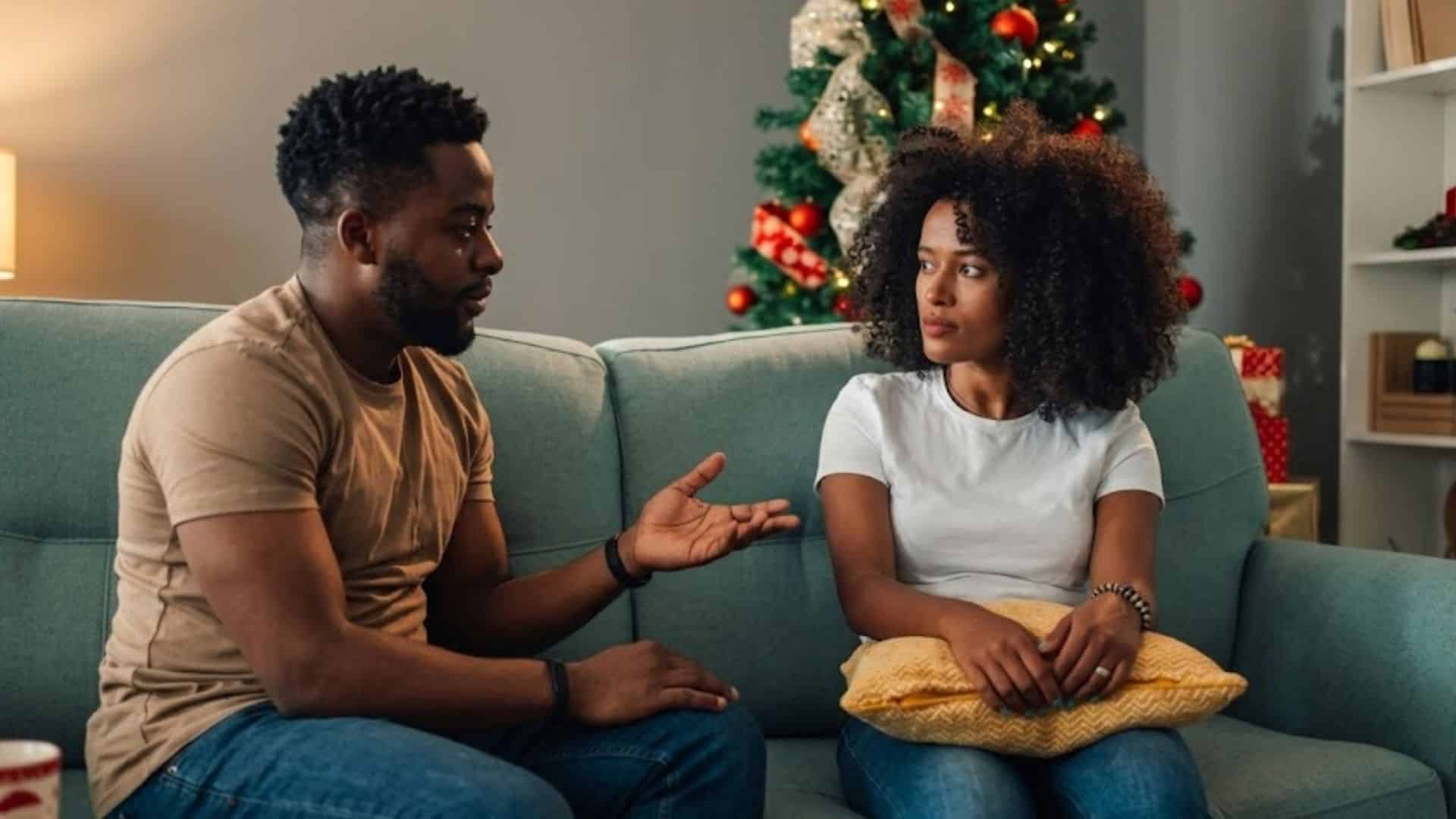 An African American couple sits on a living room sofa, engaged in an earnest conversation