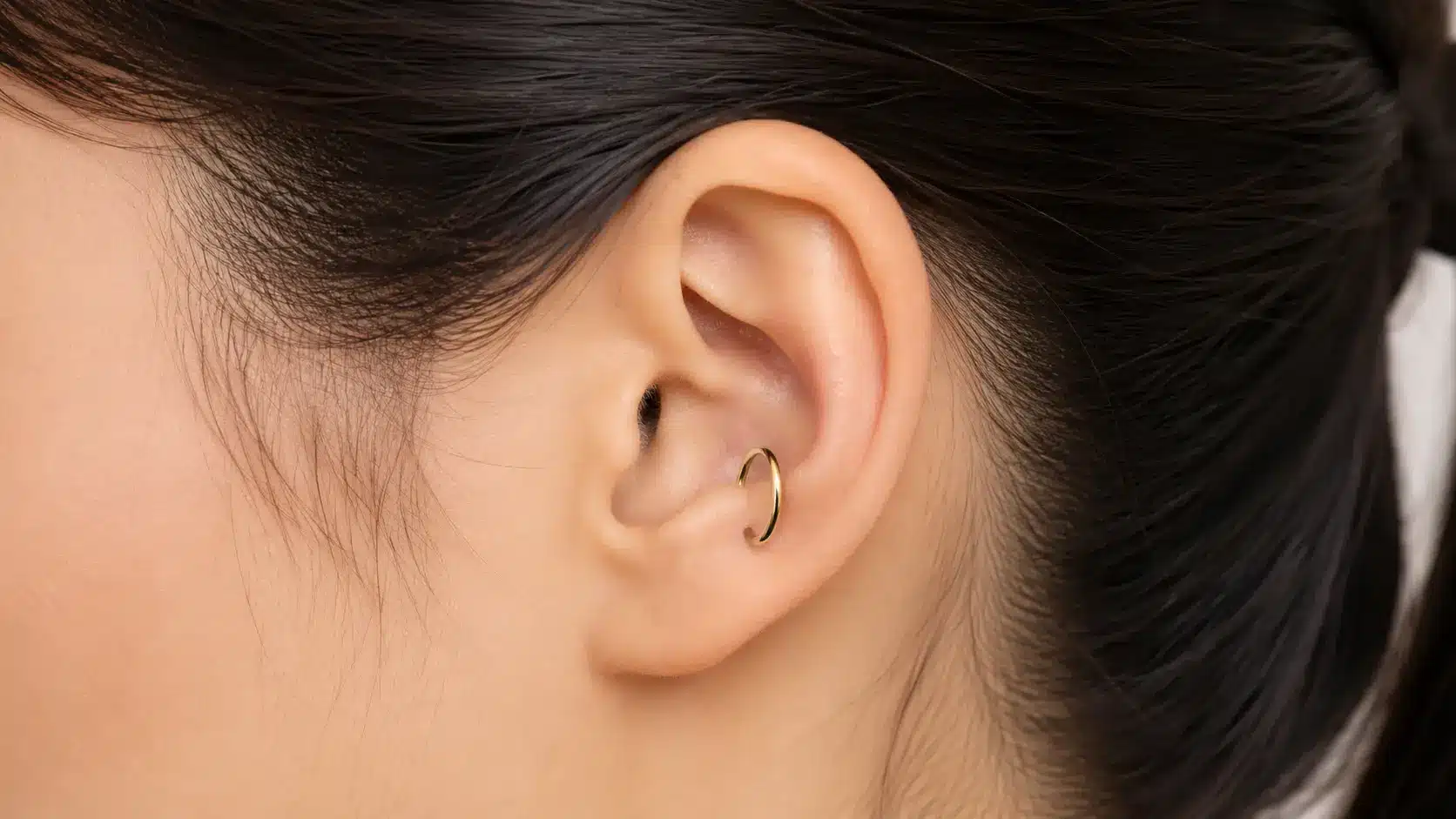 Anti-Tragus Piercing with a small gold hoop inside the ear cartilage