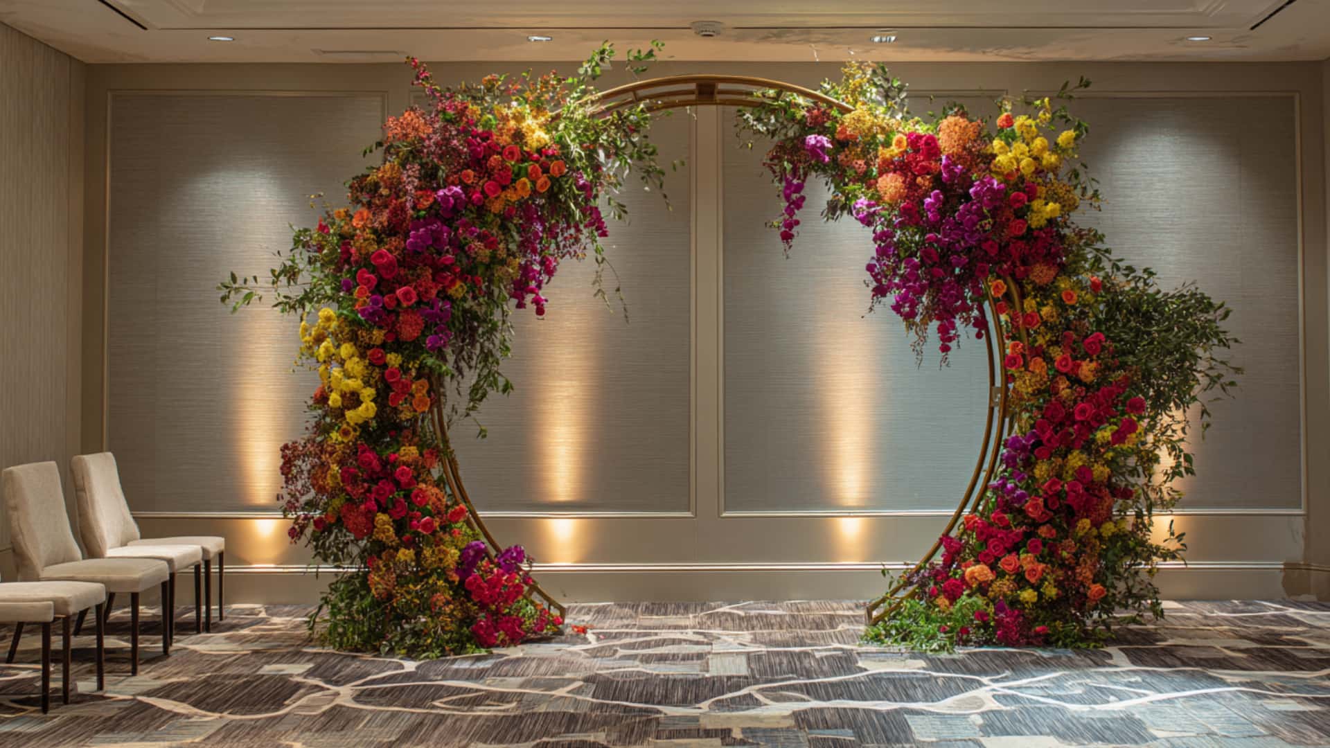 Colorful circular floral wedding arch in a modern indoor ceremony space, glowing.