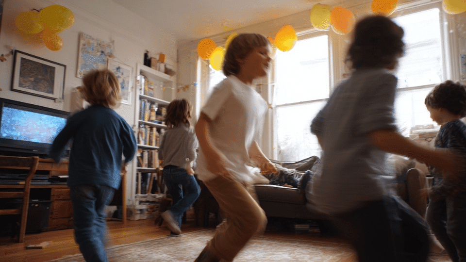 Kids playing games at a lively indoor birthday party in a real home setting