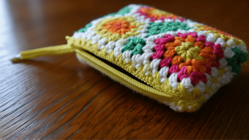 Crochet mini zipper pouch with zipper partially open holding small essentials