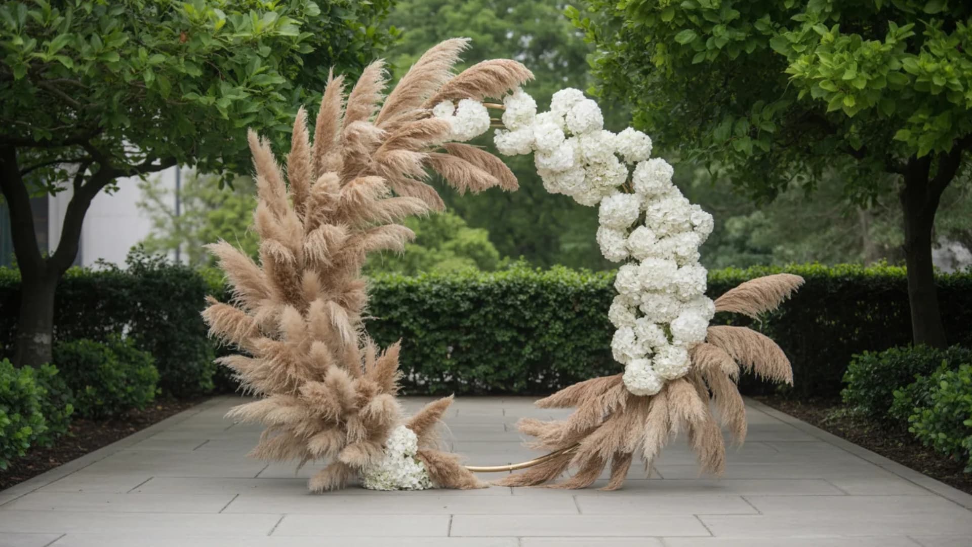 Round wedding arch with pampas grass and white blooms in a serene garden pathway.