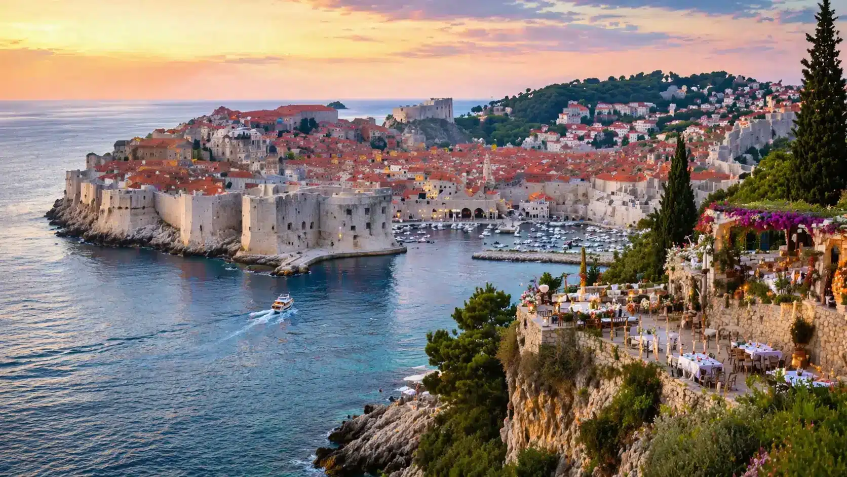 Stunning sunset view of Dubrovnik, Croatia, showcasing its ancient stone walls, red-tiled roofs, and a yacht sailing .