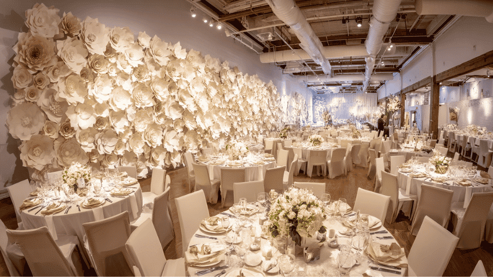 Wedding reception with large paper flower wall photo backdrop and full venue setup