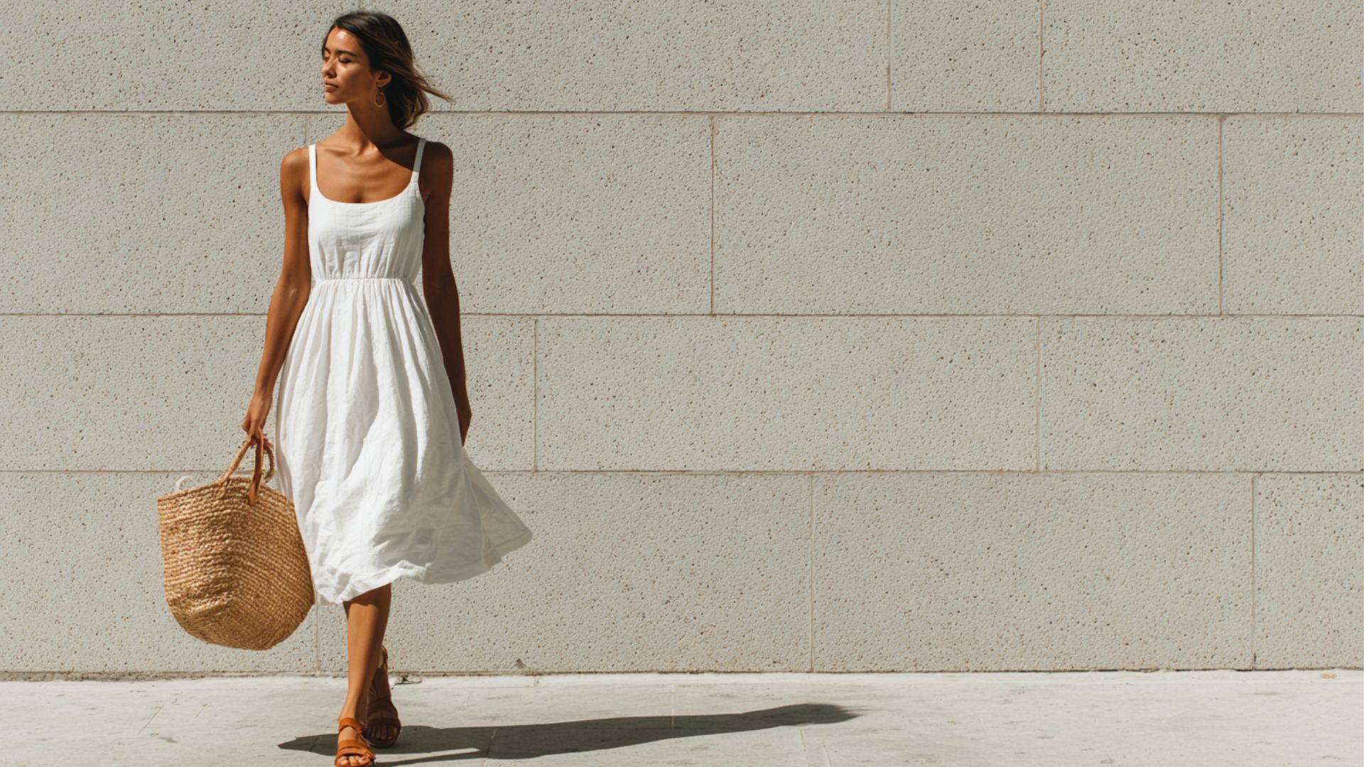 Woman wearing a casual sleeveless white cotton A-line sundress with thin straps, knee-length flared skirt