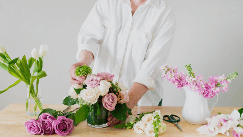 a person making flower bouquet using flower arrangement setby H.Bloom
