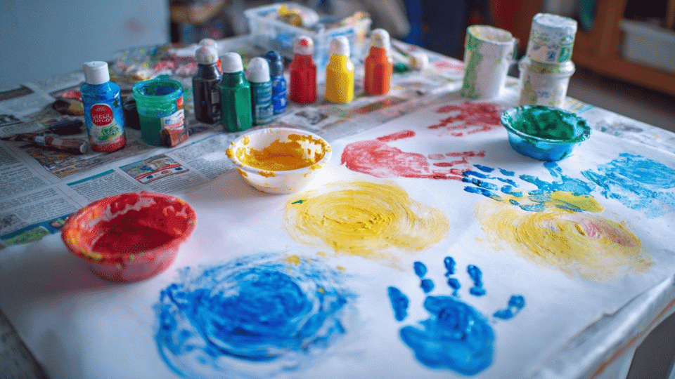 Finger painting with homemade paints on table with bowls and newspaper.