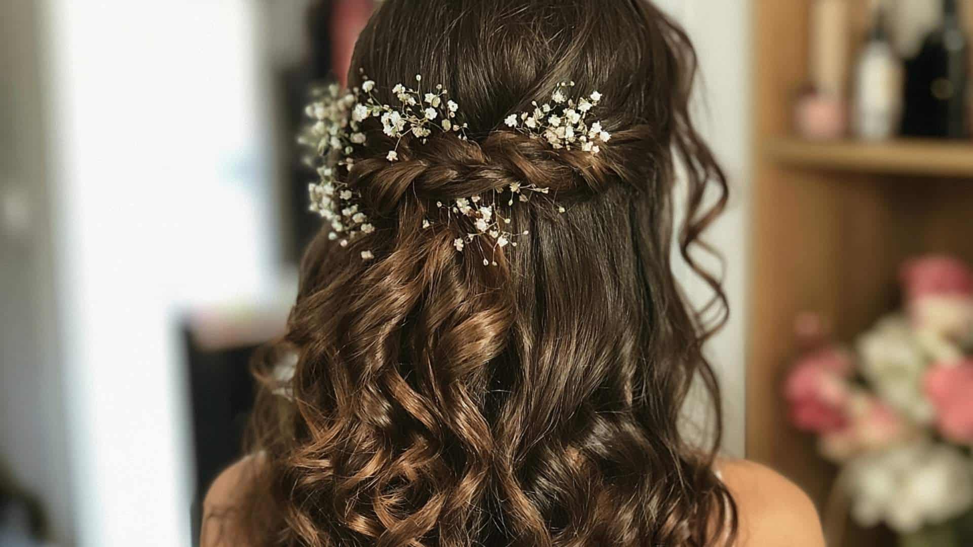 Back view of a bride with small babys breath flowers placed through a soft half up twist and curls in soft light