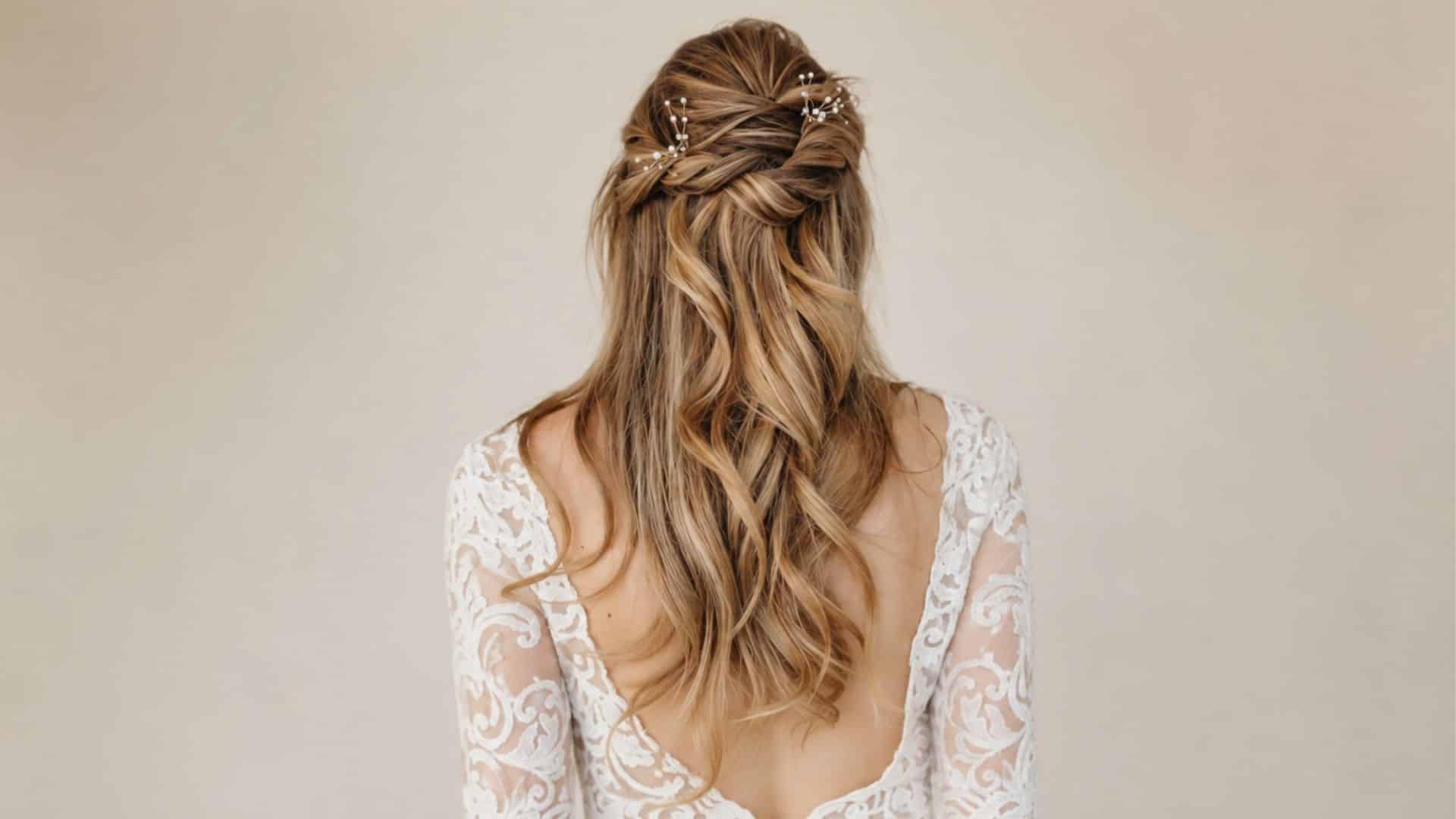 Boho half up half down wedding hairstyle with loose blonde waves, twisted crown sections, and delicate pearl hair pins