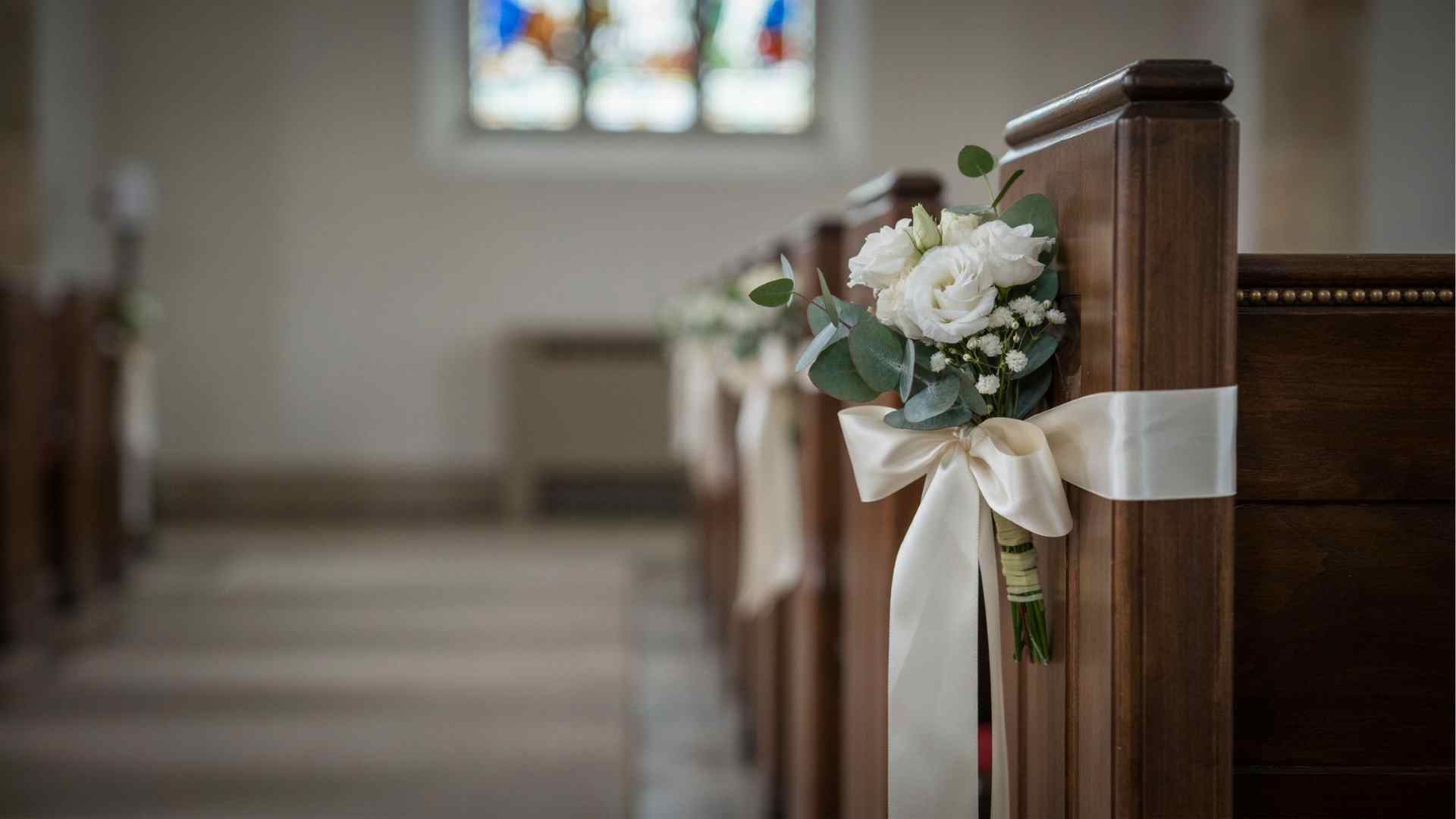 DIY ribbon and faux flower decorations attached to church pews