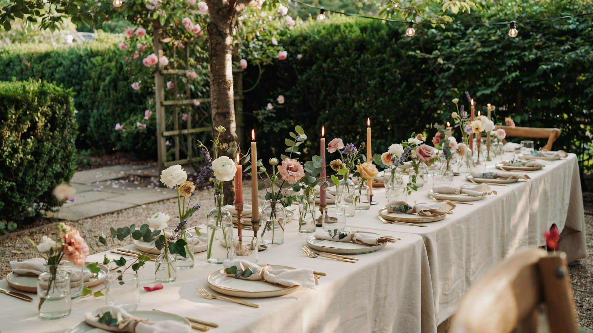 Elegant wedding table setting with rose flowers, eucalyptus greenery, candles, and botanical place cards