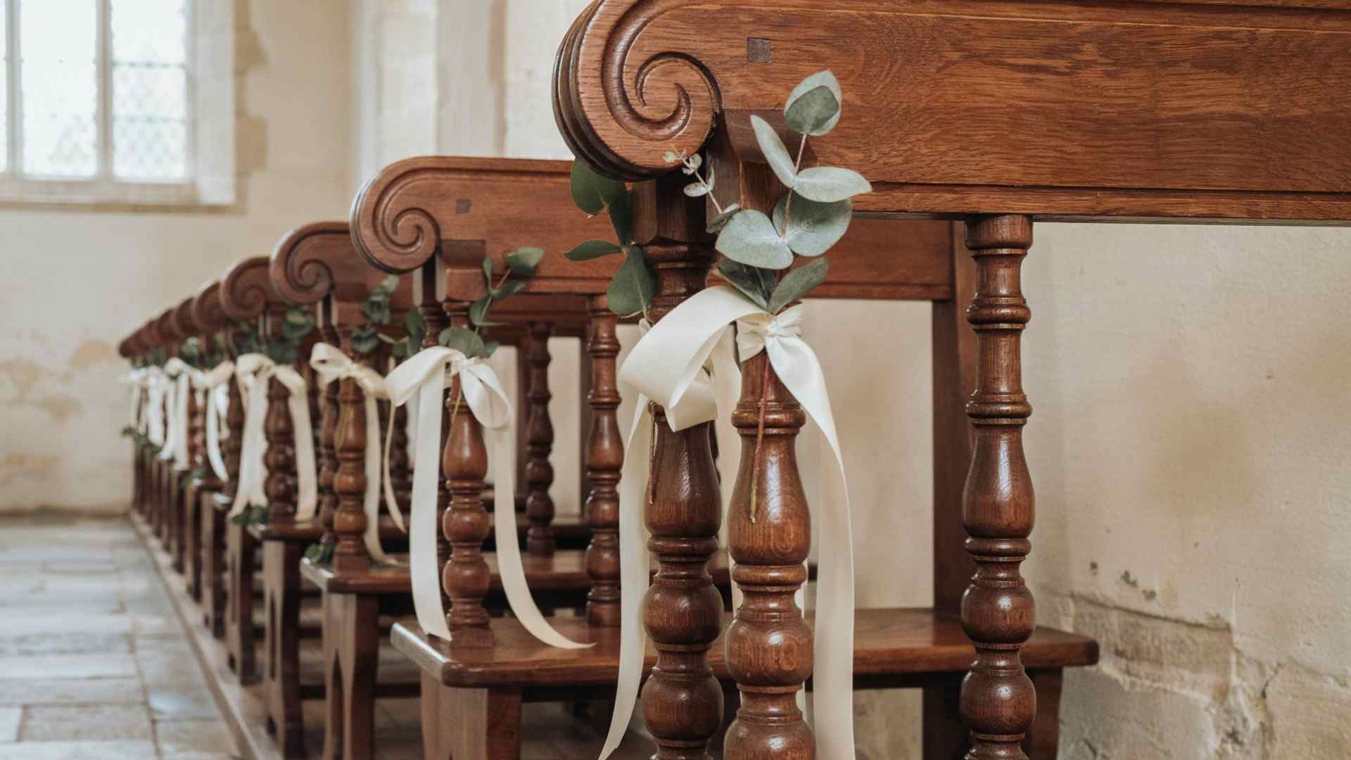 Eucalyptus stems arranged in ribbon loops on church pews