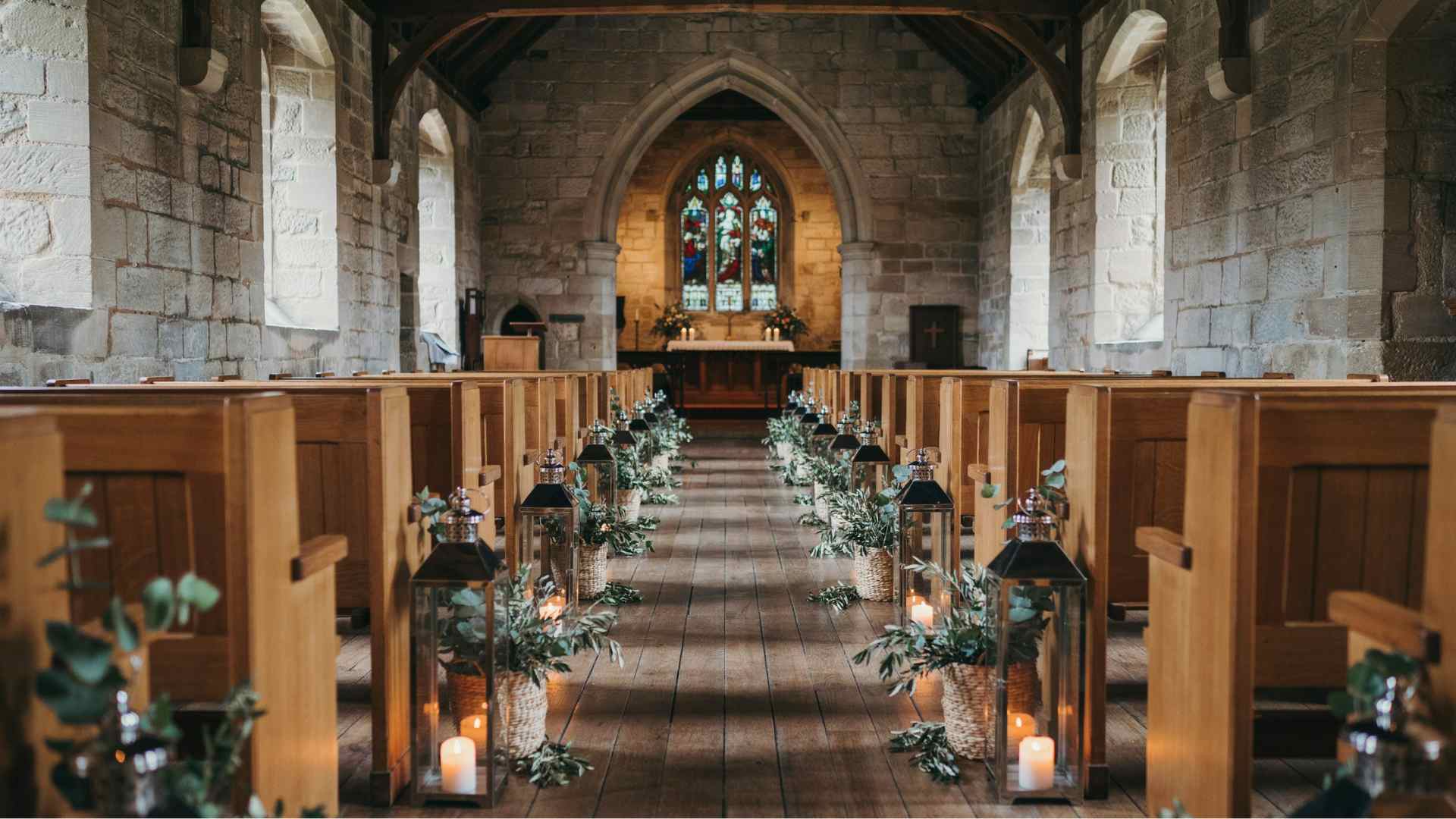Lanterns with flameless candles beside a church wedding aisle