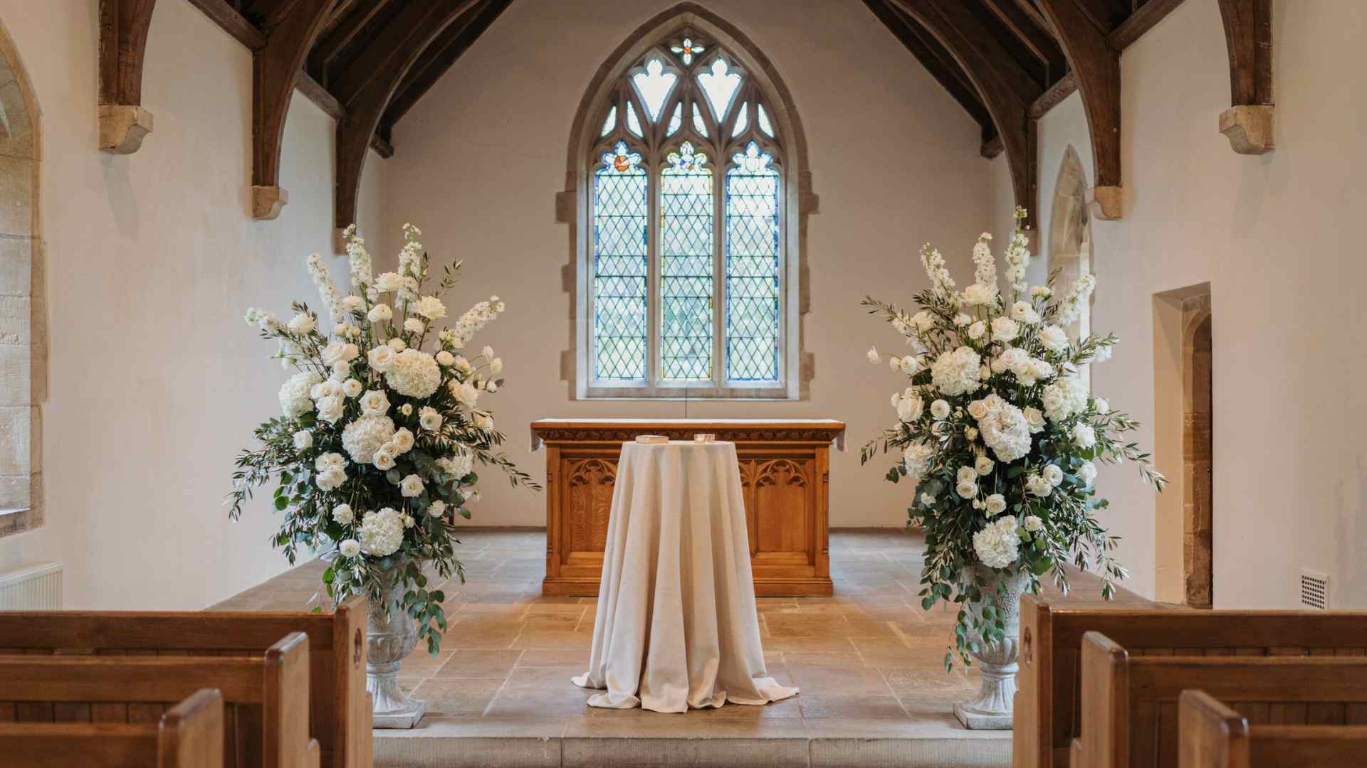 Matching floral urns framing a church wedding altar