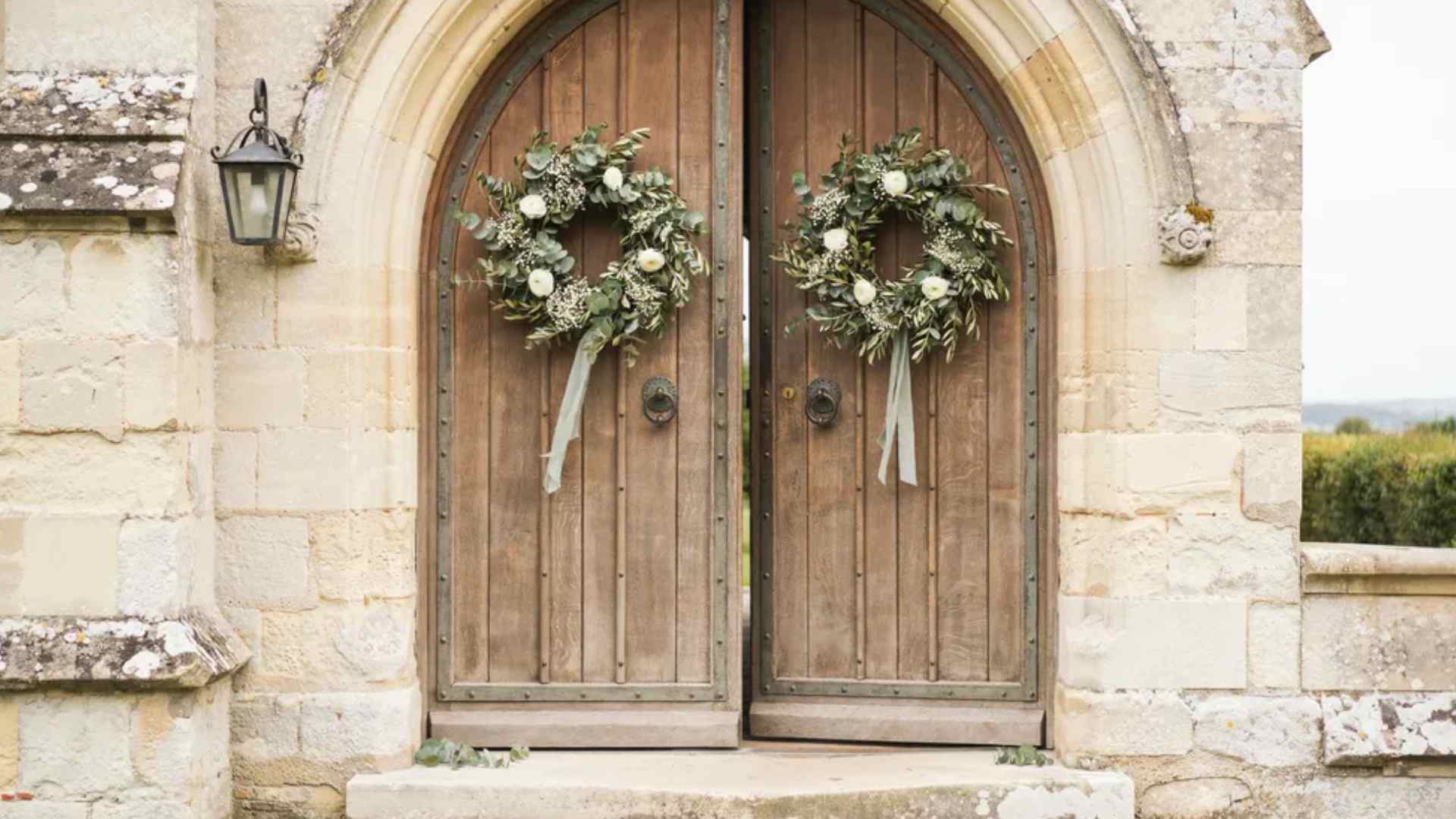 Matching greenery wreaths decorating church wedding entrance doors