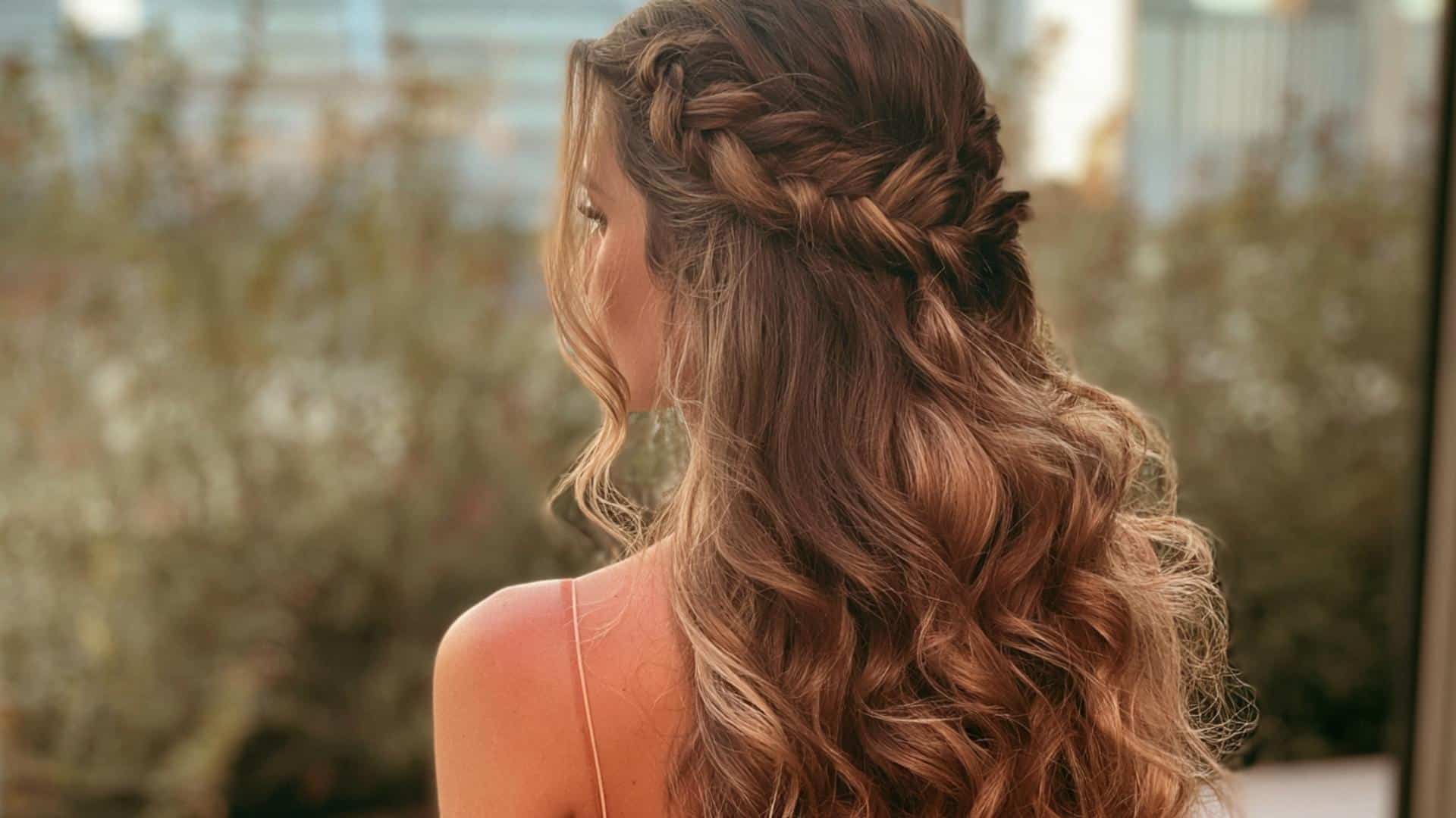 Rear view of bridal hair with one crown braid blending into a half up style and loose curls with natural flyaways