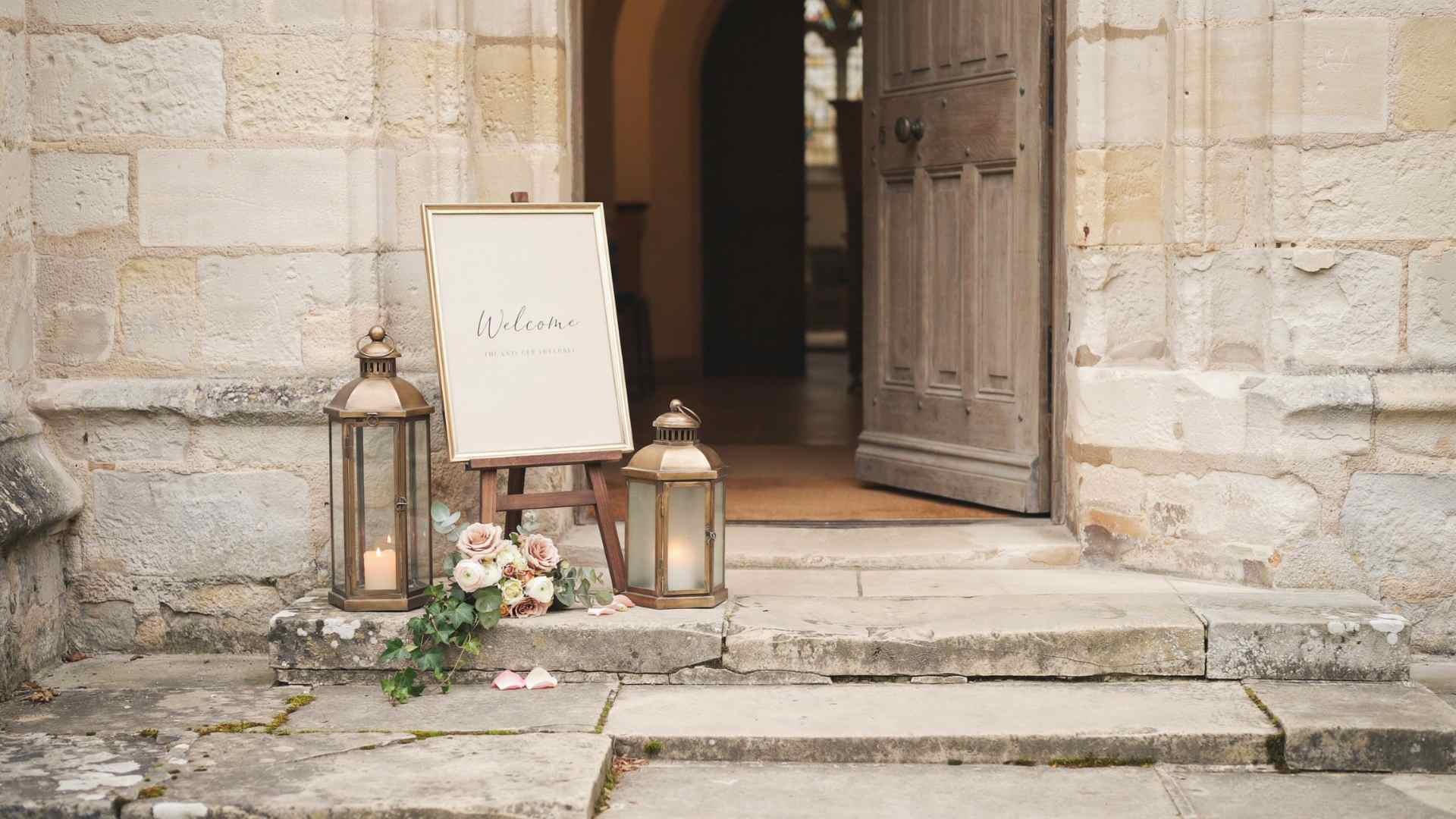 Wedding welcome sign and lanterns outside a church entrance