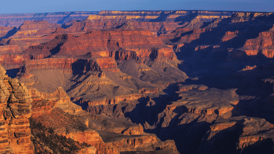Expansive layered red rock cliffs and deep valleys across Grand Canyon National Park in Arizona.