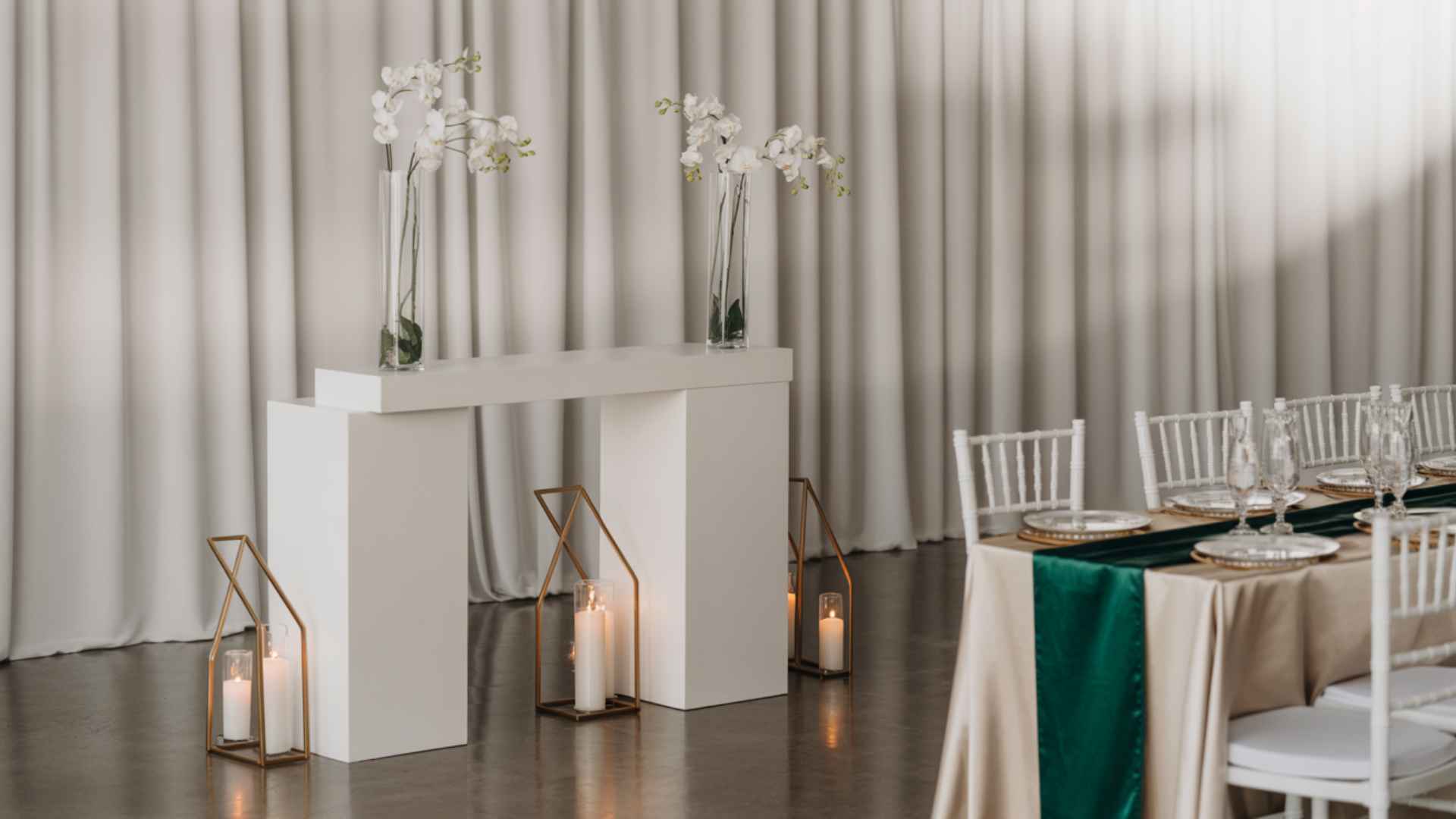 Sleek minimalist wedding with white backdrops, single-stem florals, candles.