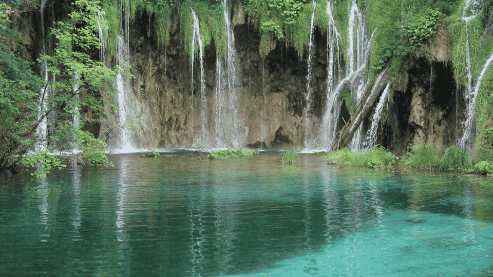 Turquoise lakes and cascading waterfalls surrounded by lush forest in Plitvice Lakes National Park.