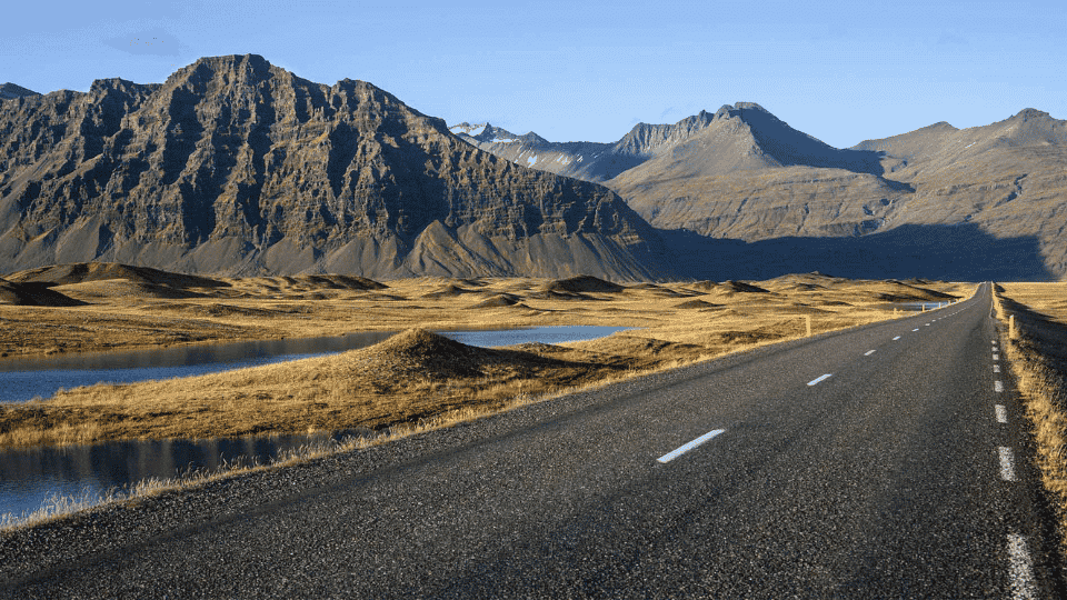 Iceland's Ring Road passing dramatic mountains, waterfalls, and rugged volcanic landscapes.